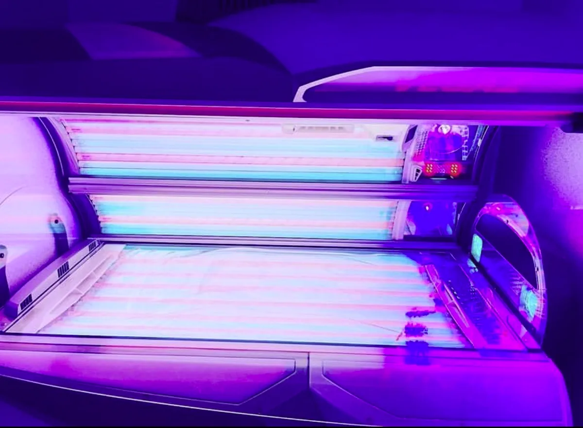 Top-down view of an open premium sunbed in violet light